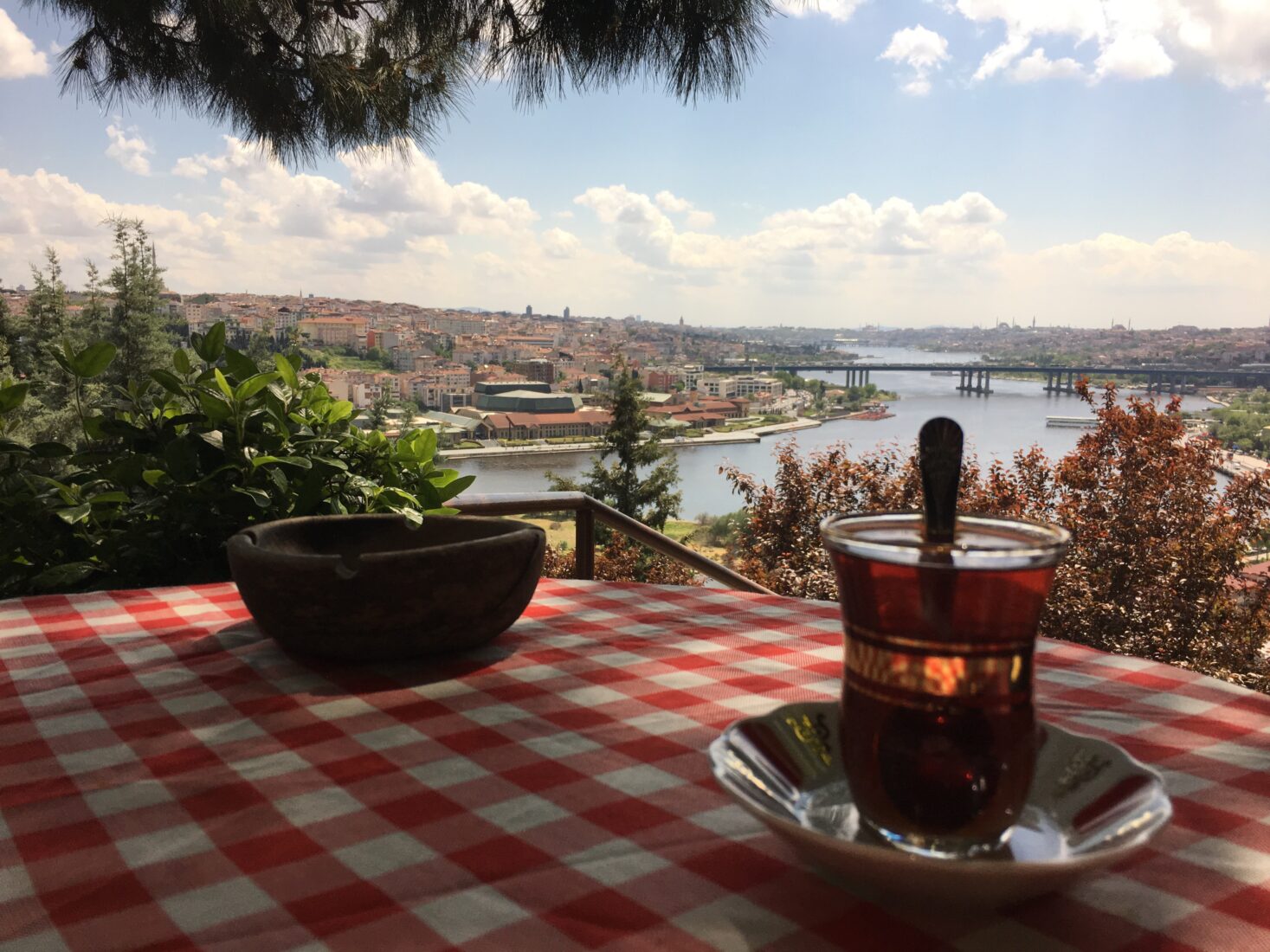 Turkish tea served in a special glass on a table, a view of the Golden Horn from Pierre Loti Hill, Istanbul, Türkiye. (Adobe Stock Photo)