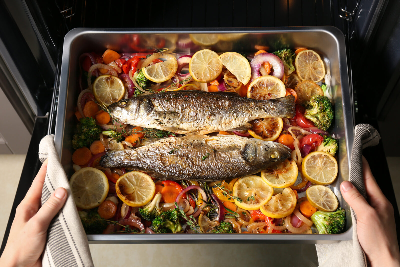 A beautifully roasted whole fish with sumac, onions, and lemon slices, baked to perfection with fresh vegetables. (Adobe Stock Photo)