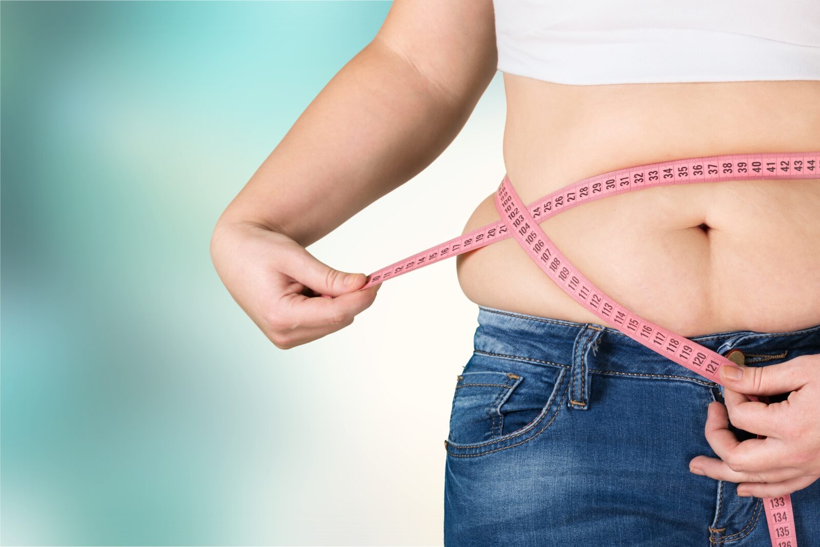 A woman measures her waist as part of weight management and health monitoring efforts. (Adobe Stock Photo)