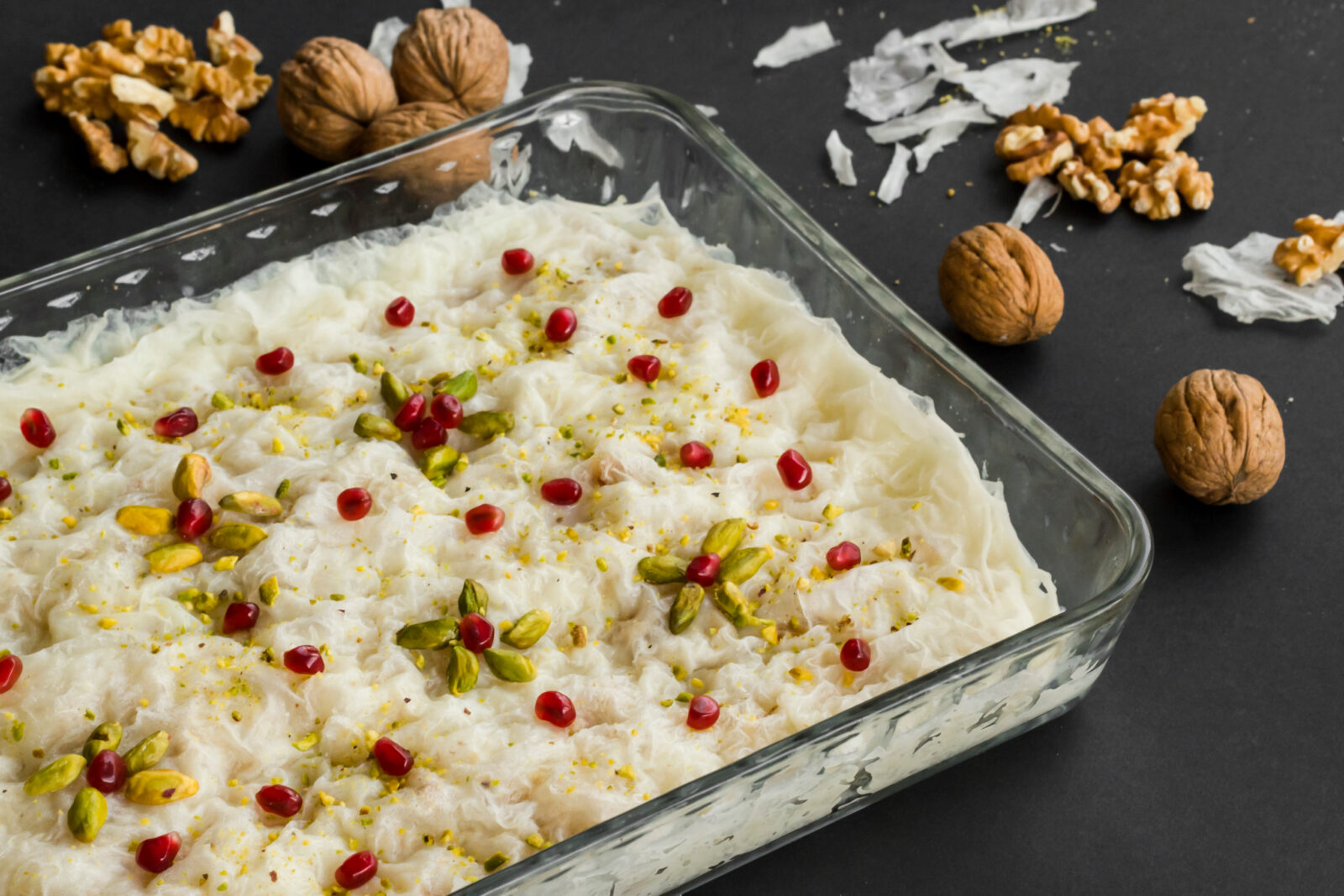 Traditional Turkish Ramadan milky dessert gullac designed in glass container on black with walnuts. (Adobe Stock Photo)
