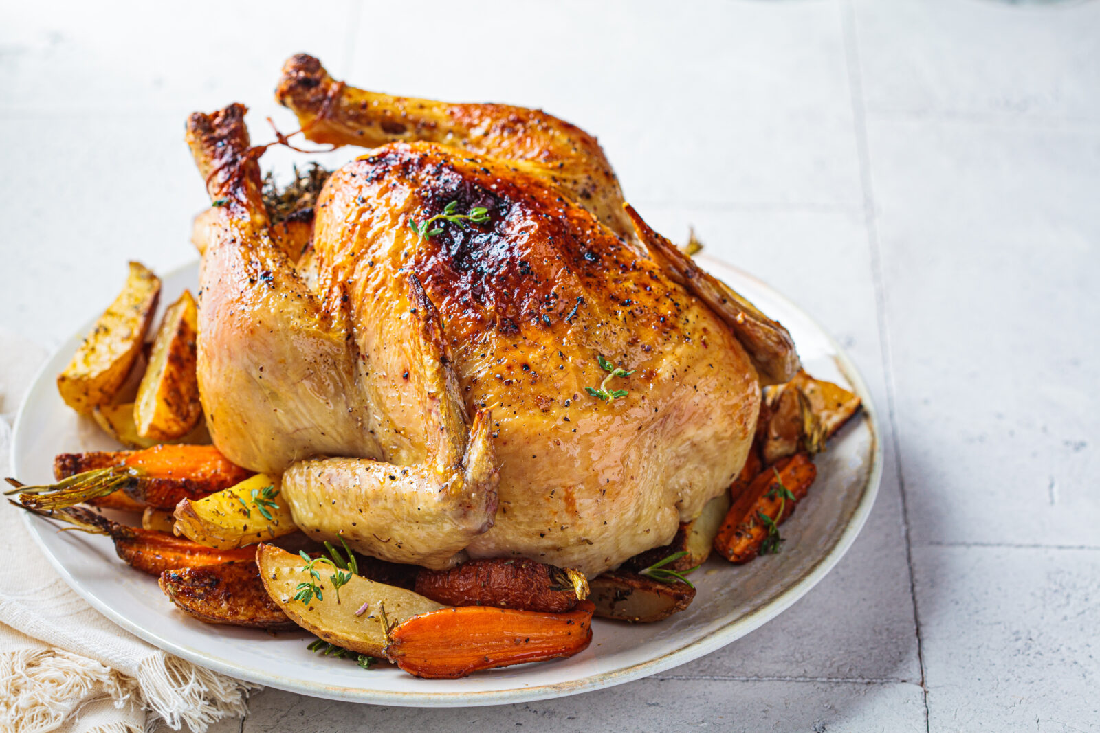 Golden roasted stuffed chicken with crispy skin, served on a bed of seasonal vegetables for the iftar main course. (Adobe Stock Photo)