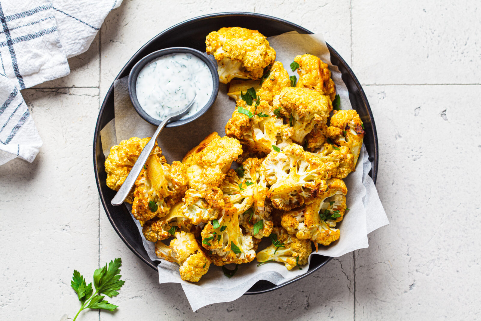 Crispy oven-roasted cauliflower (Karnabahar Kizartmasi) with a side of garlic yogurt dip adds a savory crunch to the iftar spread. (Adobe Stock Photo)