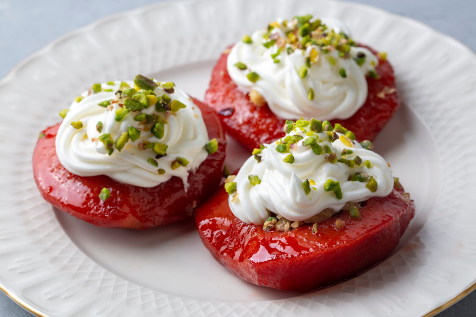 A Turkish recipe featuring baked quince topped with cream and crushed pistachios, a sweet way to end iftar. (Adobe Stock Photo)