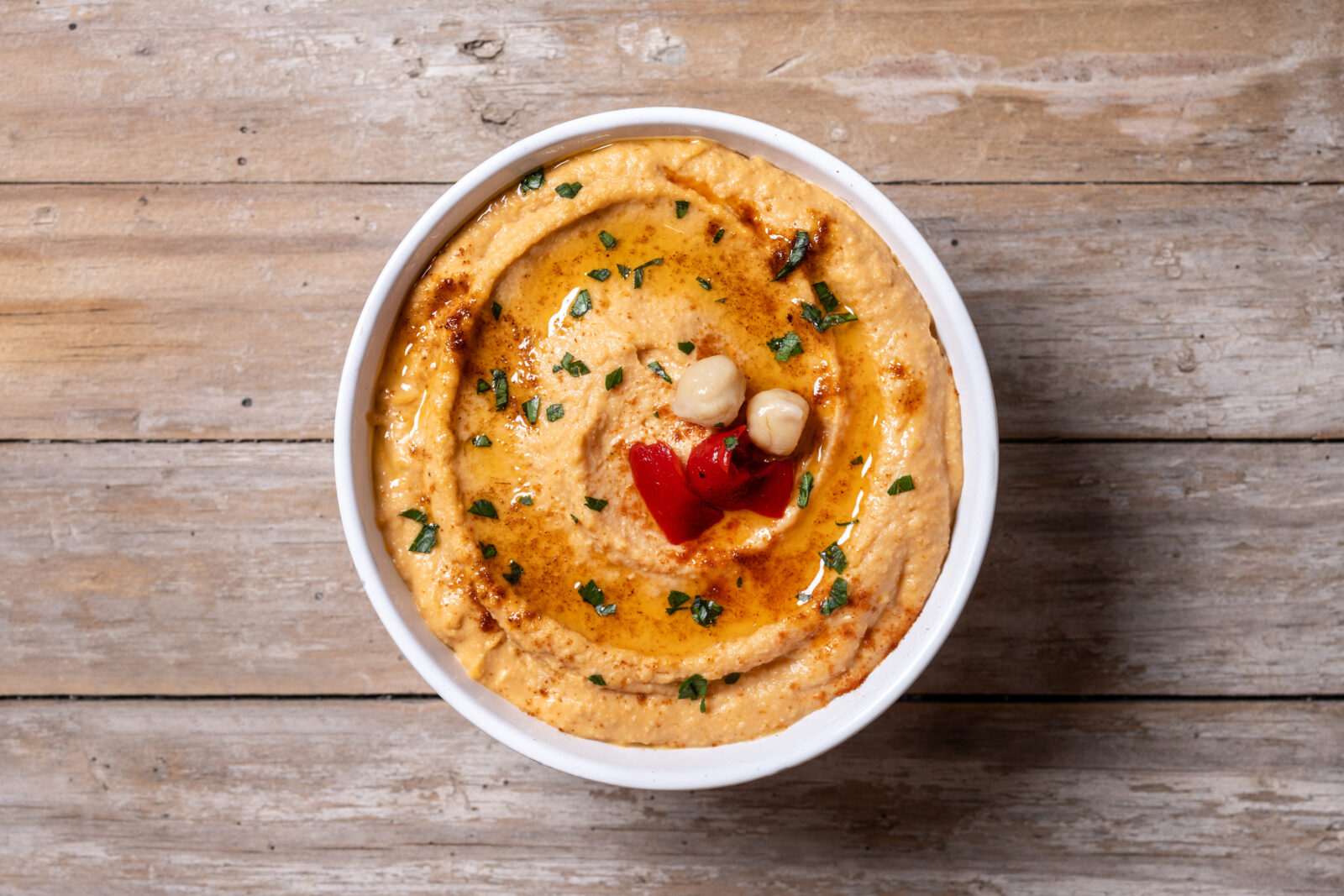 A creamy bowl of chickpea hummus topped with paprika butter, a delicious appetizer for iftar. (Adobe Stock Photo)