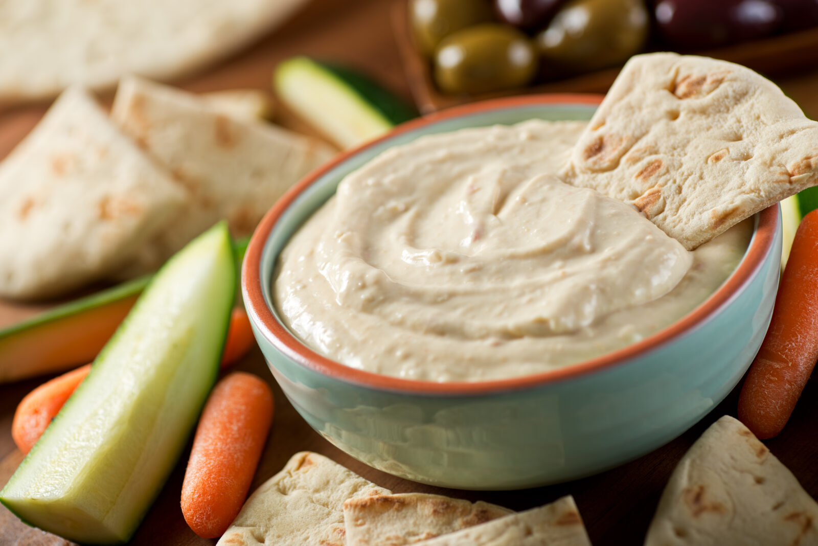 A bowl of creamy zucchini and tahini dip is served with pita bread and fresh vegetables. (Adobe Stock Photo)