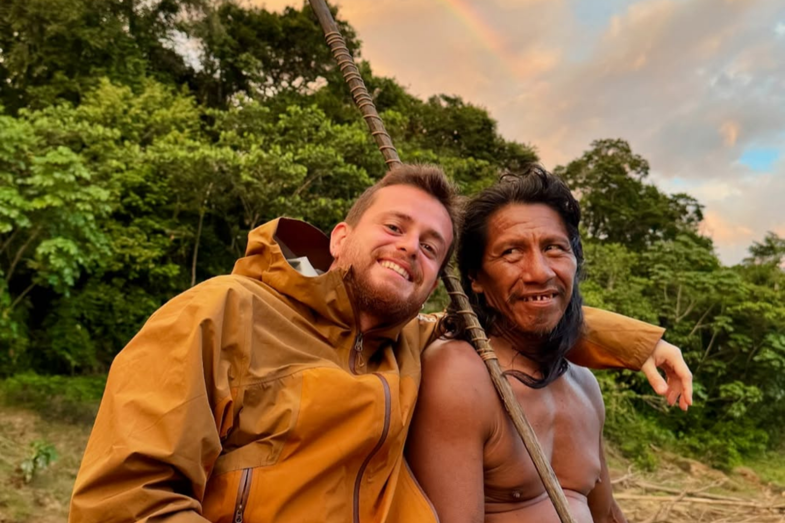 Turkish influencer Alper Rende and a Waorani hunter smile together in the Amazon rainforest, with a rainbow in the background, Ecuador, Aug. 24, 2024. (Photo via Instagram / @alperrende)