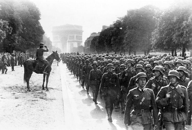 German soldiers march through the streets of Paris during the Nazi occupation of World War II, with the Arc de Triomphe visible in the background, France. (Photo via Türkiye Daily)