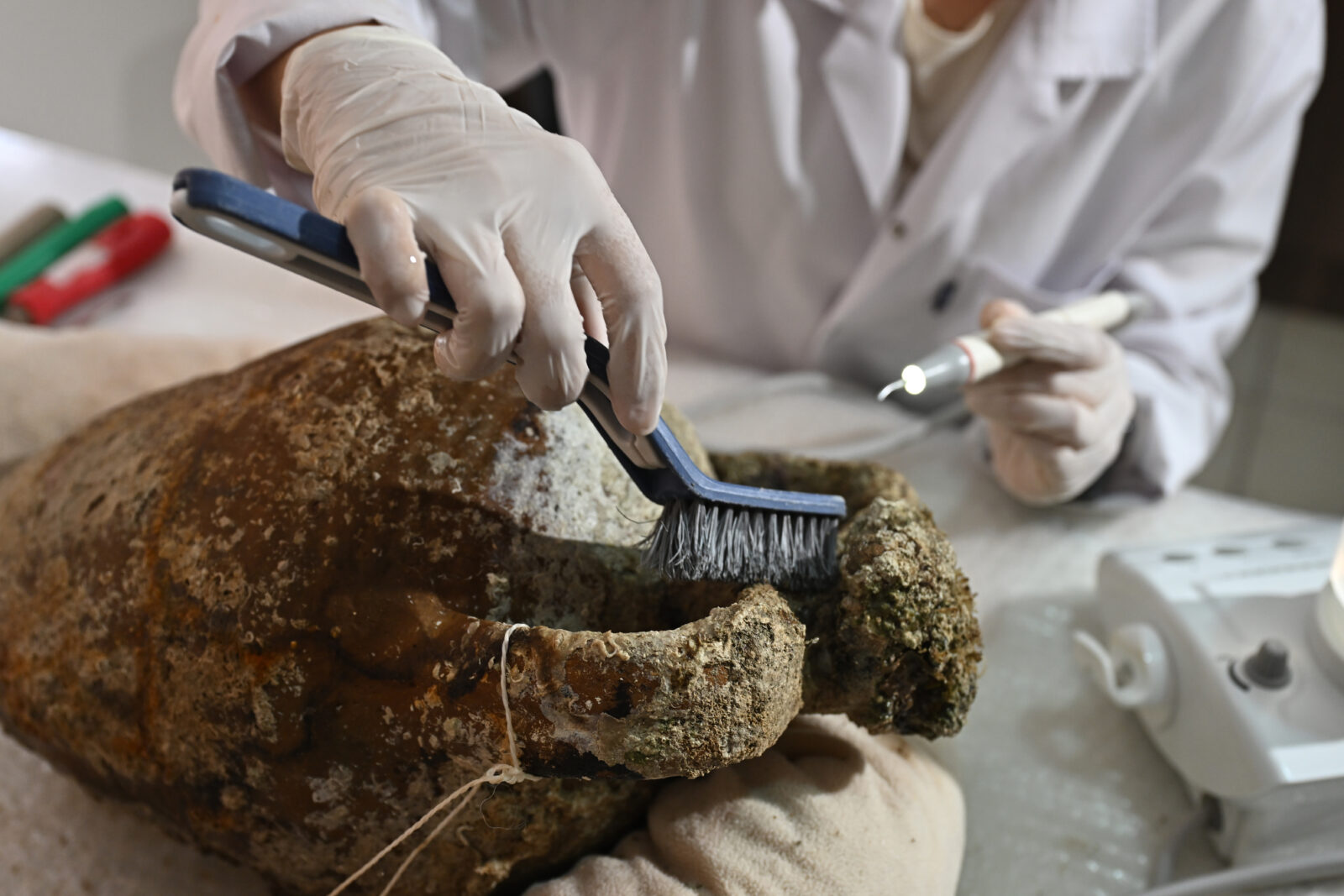 An expert works on a 1,100-year-old, closed-mouth amphora (a jug used in ancient times) that was removed from a shipwreck during underwater excavations carried out with the help of robots off the coast of Kas, Antalya, Türkiye, April 22, 2025. (AA Photo)