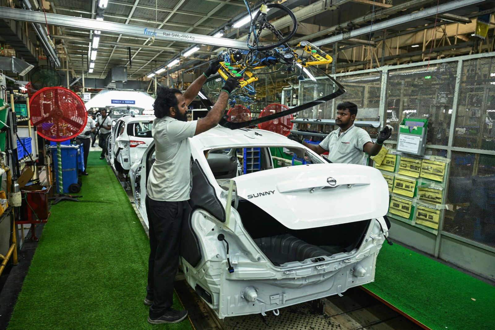 Workers assemble a Nissan Sunny on factory line