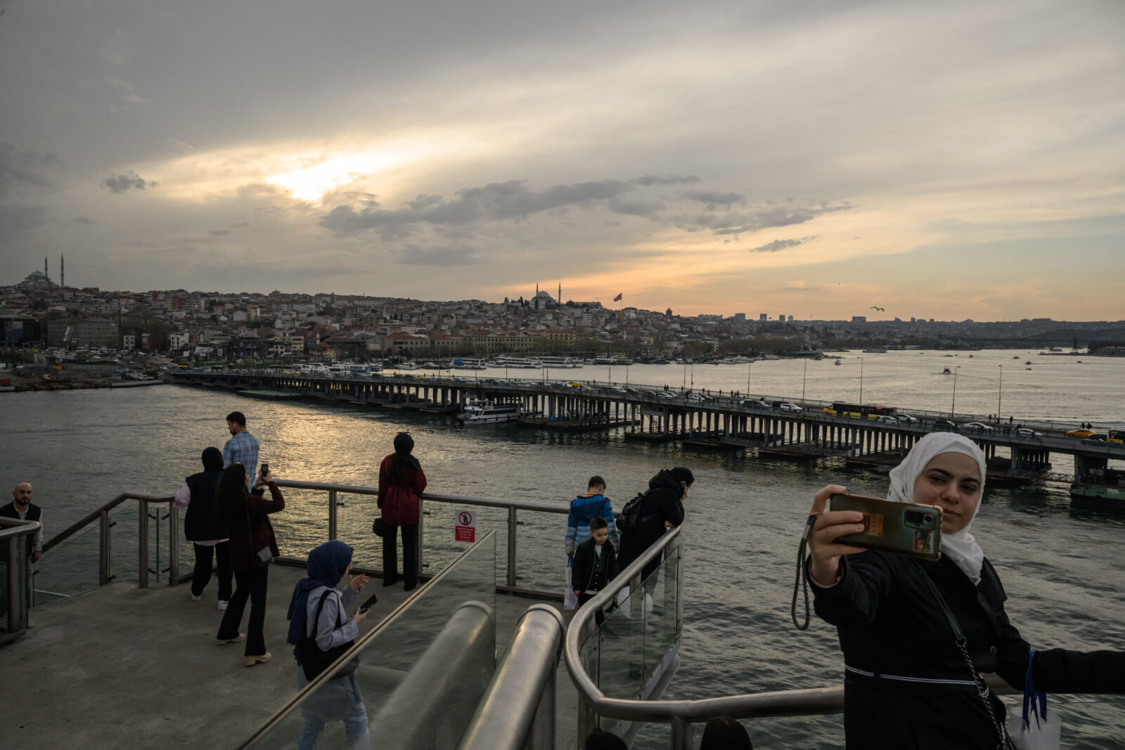 People stand on the Halic Metro Kop (Golden Horn Metro Bridge) in front of the Ataturk bridge and Bosphorus, in Istanbul, Türkiye on March 31, 2025. (AFP Photo)