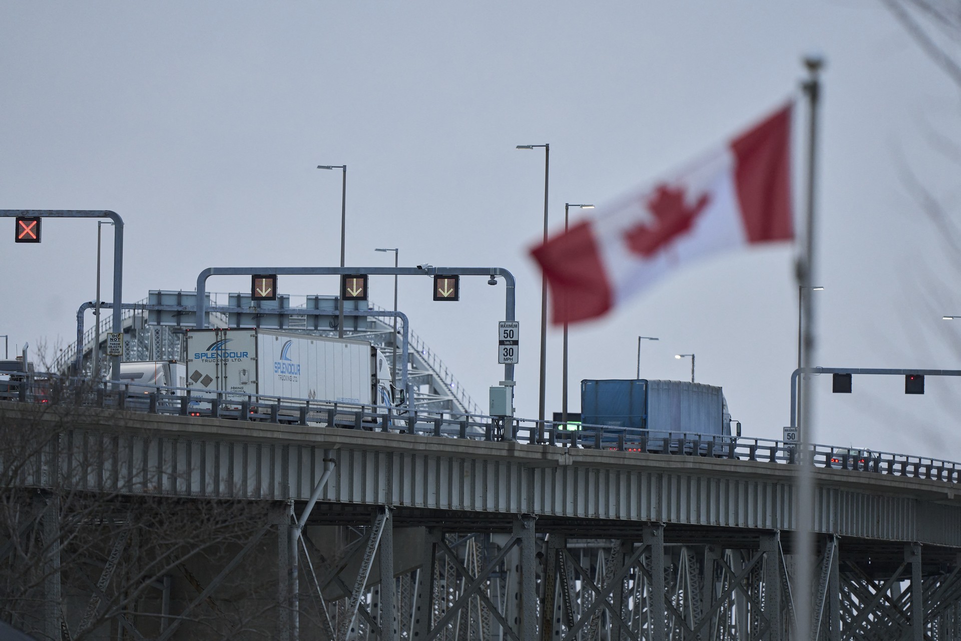 Trucks cross the Blue Water Bridge border crossing in Sarnia, Ontario, on April 1, 2025. US trading partners scrambled on April 1 to prepare for the latest raft of Donald Trump tariffs, after the US president left unclear who would be targeted but promised to be "very kind" in addressing what he says are unfair trade imbalances. Trump -- who has been making unprecedented use of presidential powers since taking office in January -- said he could announce as early as Tuesday night exactly what "reciprocal tariffs" will be imposed. (Photo by Geoff Robins / AFP)