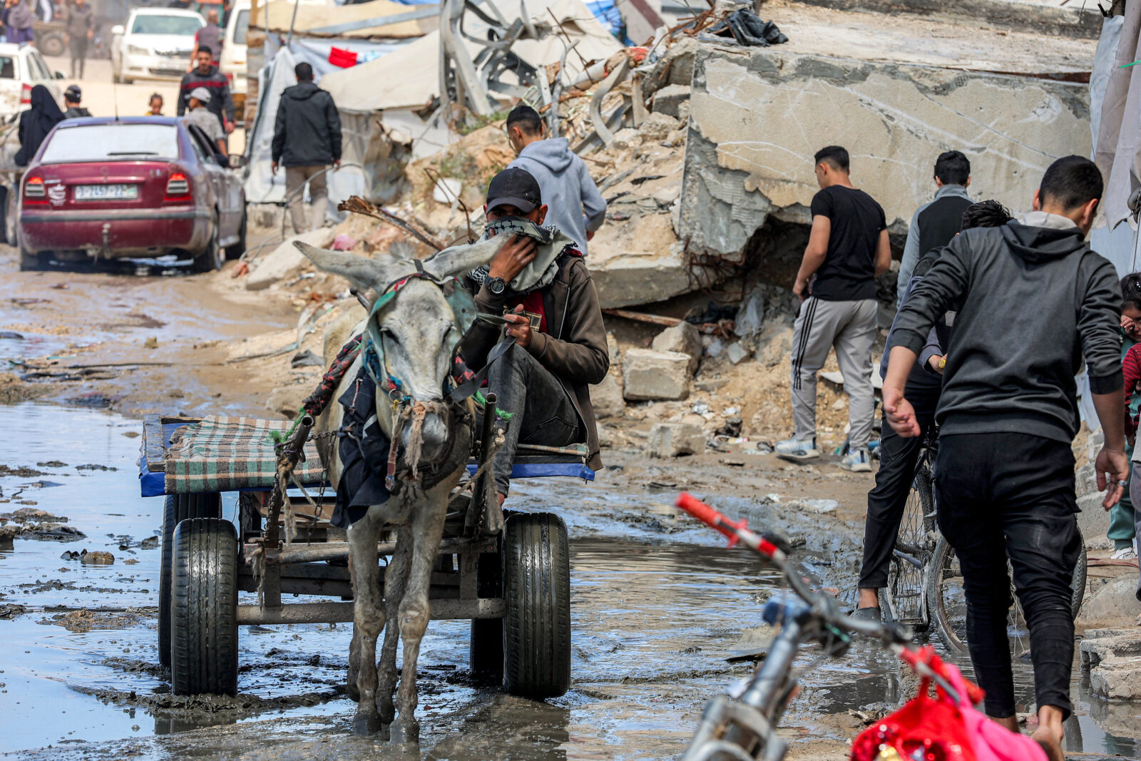 A man covers his face as he drives his donkey-drawn cart through a muddied street past the rubble of a collapsed building in the Nasr neighbourhood in western Gaza City on April 15, 2025. (AFP Photo)