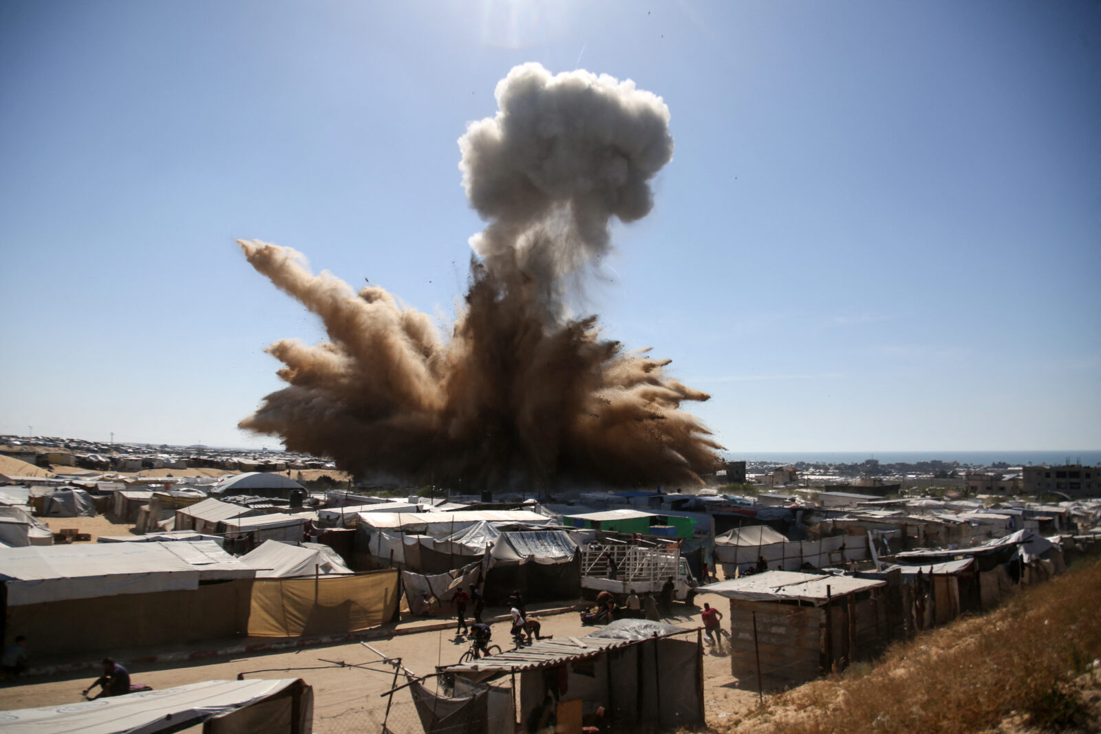 People run for cover as a plume of smoke rises above tents at a camp for displaced Palestinians during an Israeli strike in northern Khan Yunis in the southern Gaza Strip, April 19, 2025. (AFP Photo)