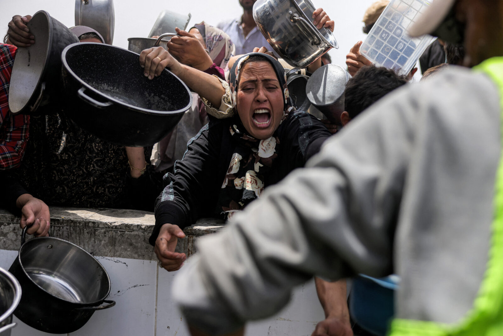 Palestinians queue with pots to receive charity meals from a kitchen in Beit Lahia in the northern Gaza Strip on April 24, 2025. (AFP Photo)