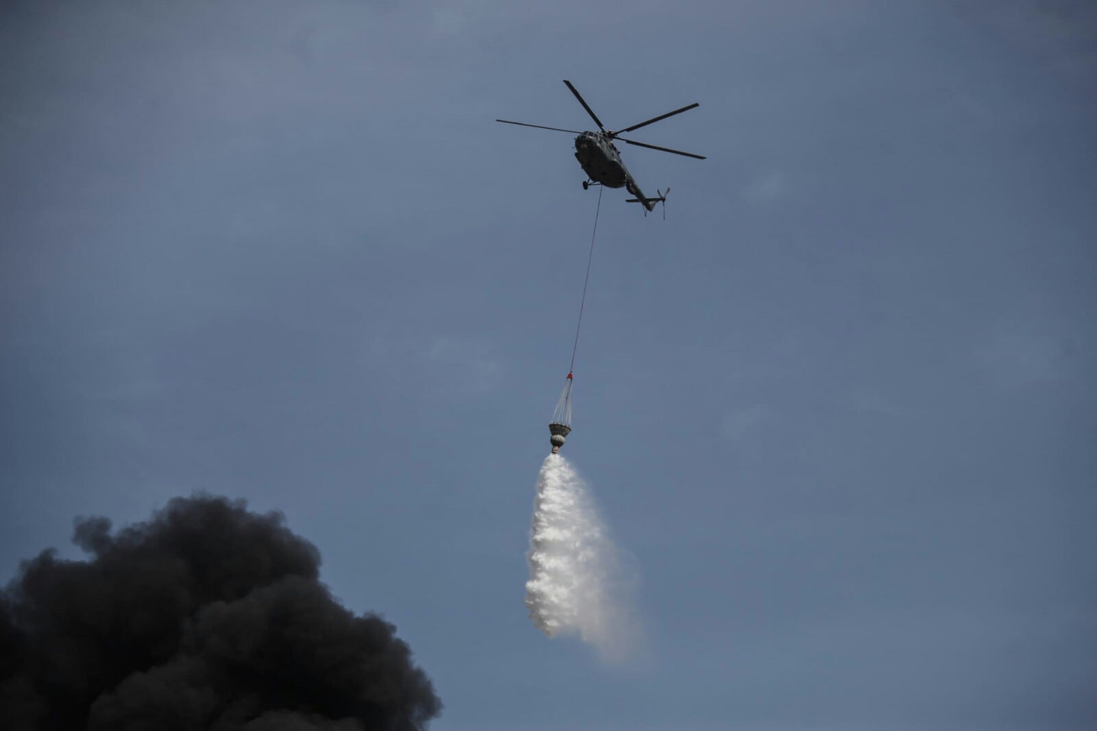 A helicopter drops water over the flames following an explosion at the Shahid Rajaee port dock southwest of Bandar Abbas in the Iranian province of Hormozgan on April 26, 2025. (AFP Photo)
