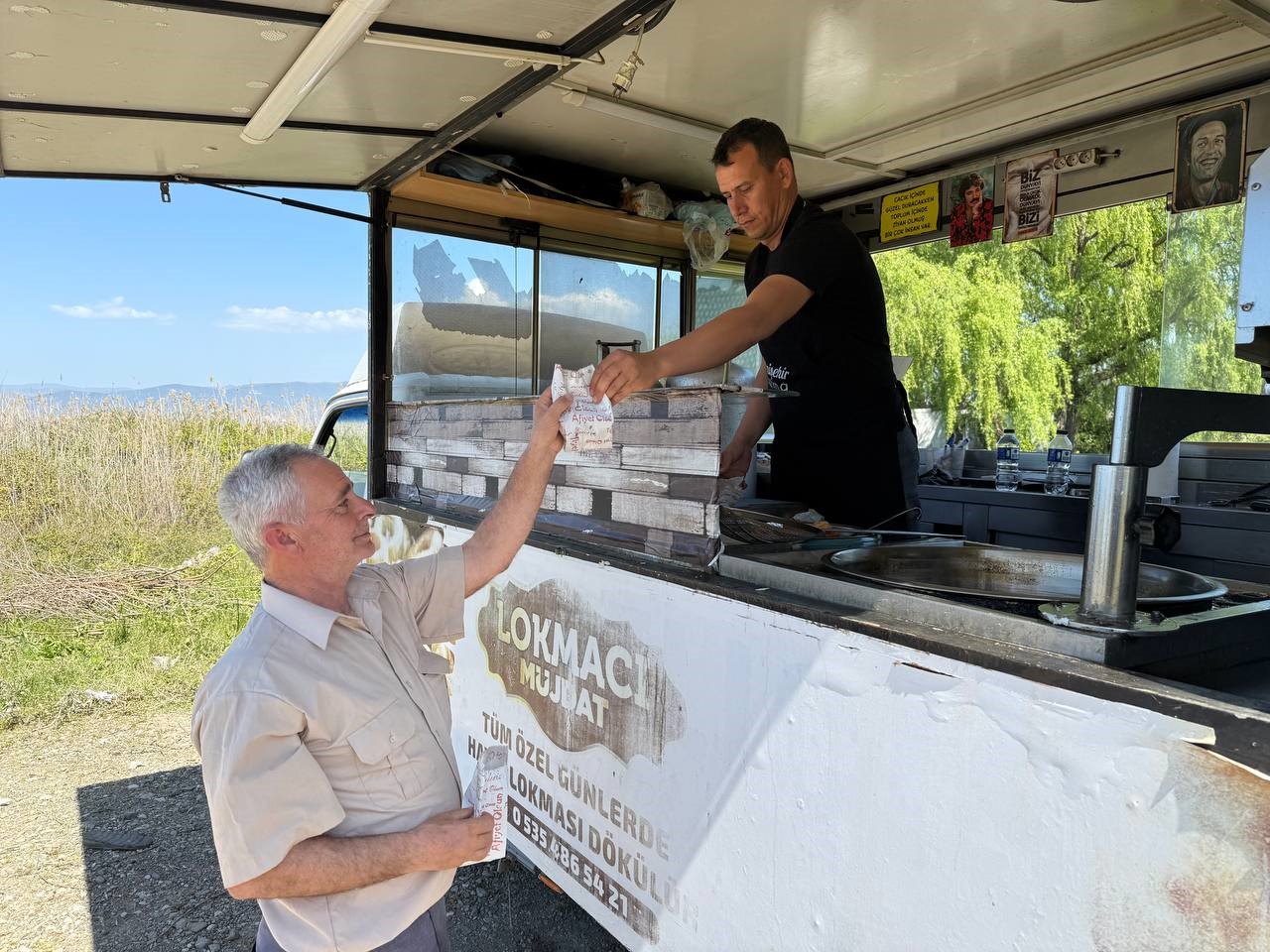 A lokma vendor hands out the traditional sweet in name of deceased Pope Francis to a resident in Iznik, Bursa on April 21, 2025. (IHA Photo)