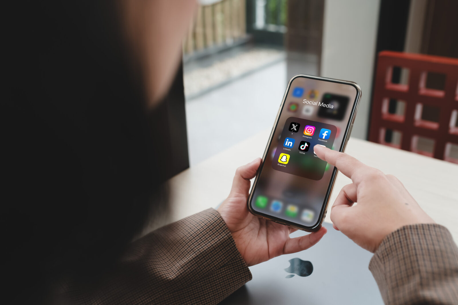A person scrolling through social media apps like Facebook, Instagram, TikTok, and LinkedIn on a smartphone in a casual workspace by the window in Bangkok, Thailand, accessed on April 26, 2025. (Adobe Stock Photo)