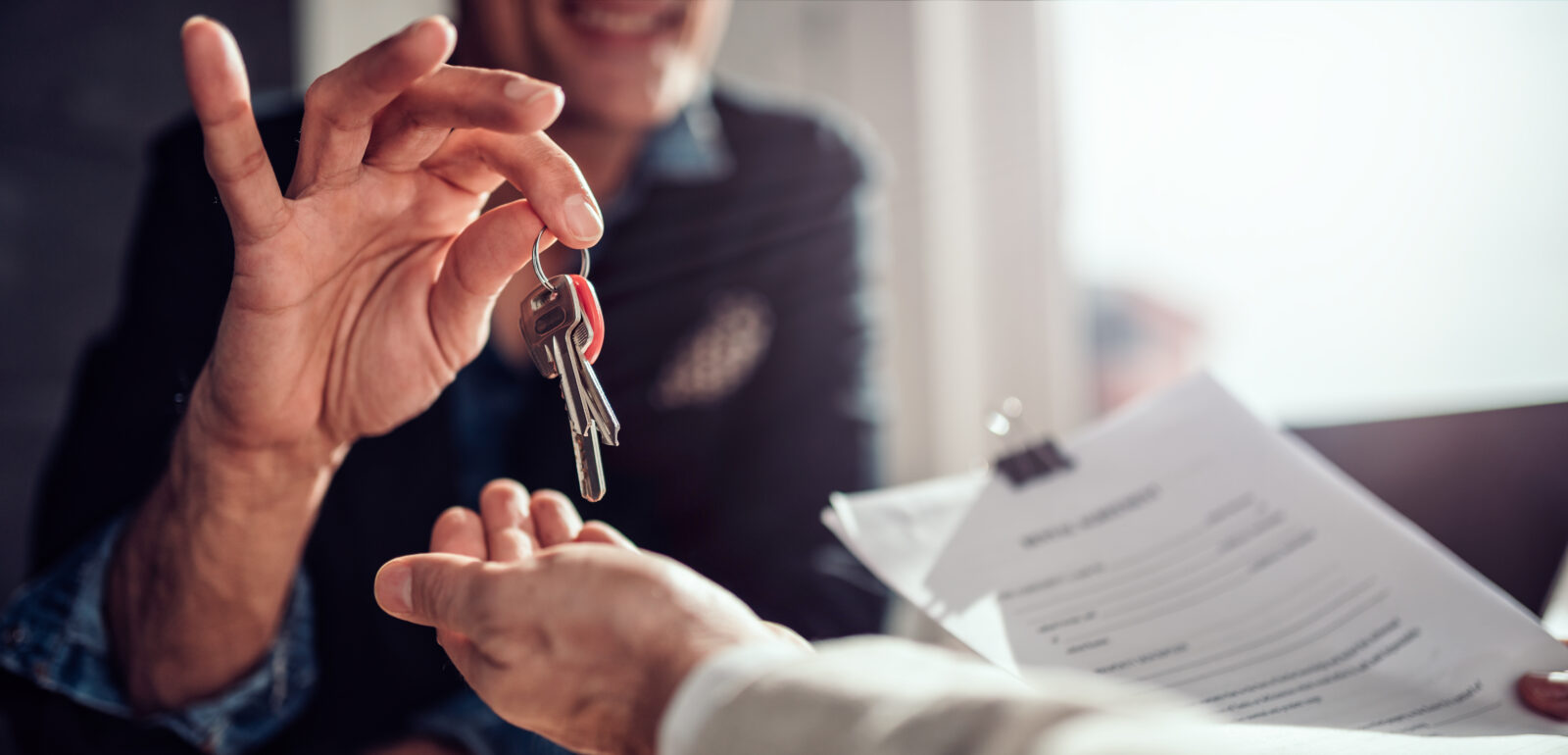 Real estate agent hands over house keys to a new homeowner or tenant, who is holding a signed contract, accessed on April 4, 2025. (Adobe Stock Photo)