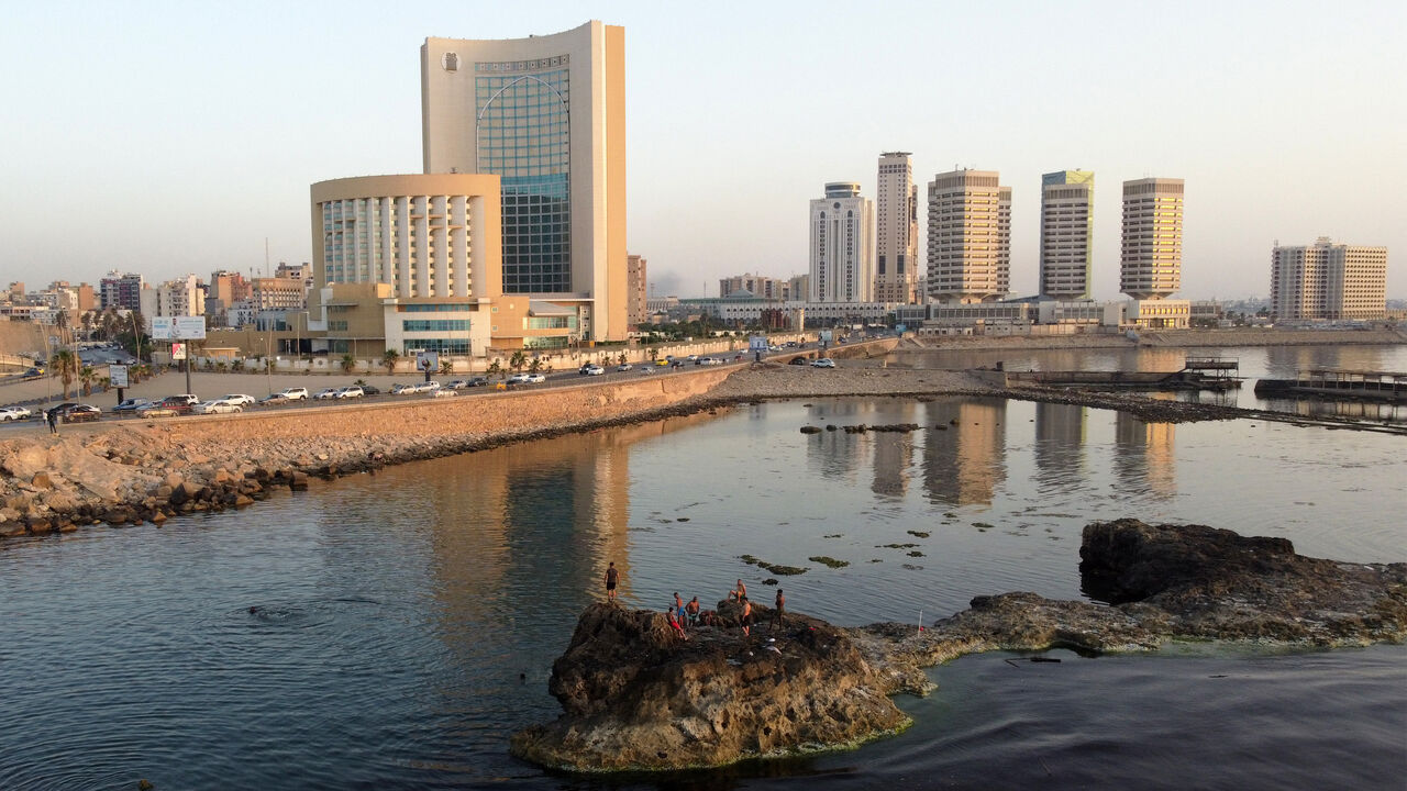 This aerial view shows youths diving into the Mediterranean sea off rocks near the landmark "That El Emad" Towers and Corinthia Hotel in Libya's capital Tripoli on July 18, 2023 as they cool off during a heat wave. (Photo by Mahmud turkia / AFP)
