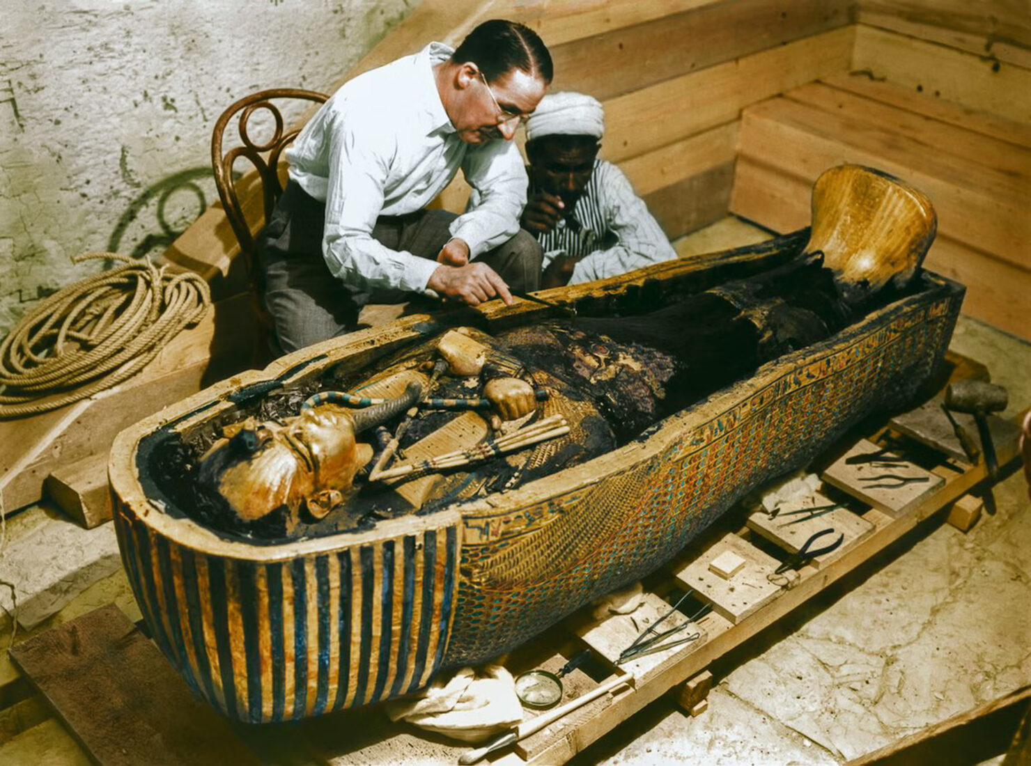 Howard Carter, who is credited with discovering King Tut’s tomb, is examining the pharaoh’s sarcophagus. (Photo via Griffith Institute)