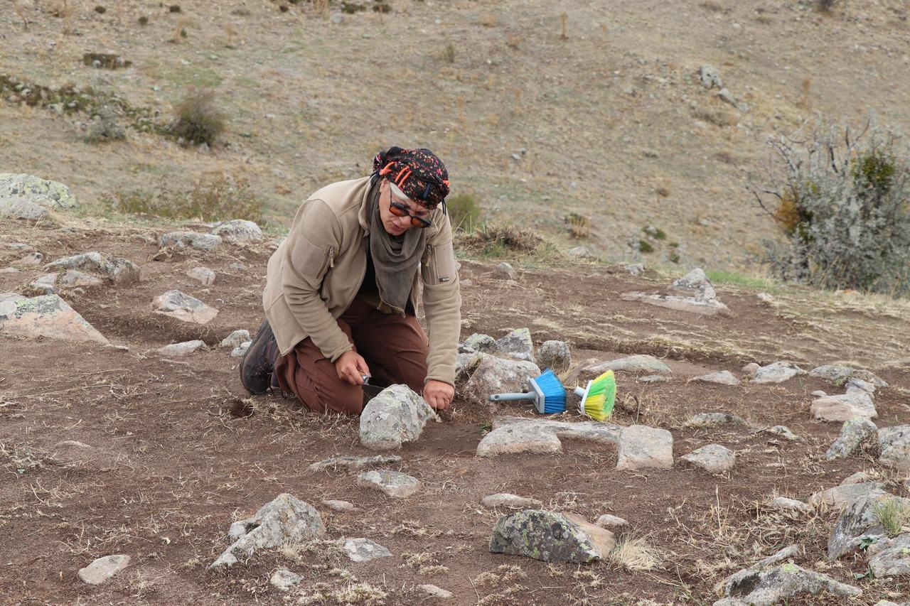 Yozgat, Türkiye'de Demir Çağı mezarlarının da bulunduğuna inanılan Kerkenes kazı alanında taşları dikkatle temizleyen bir kazı ekibi üyesi, 10 Ekim 2025. (AA Fotoğraf)