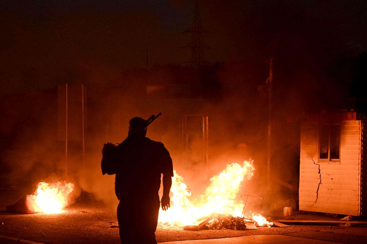 A Pakistani policeman stands in front of a burning road tax collection point after it was set on fire by angry activists of the Tehreek-e-Labbaik Pakistan (TLP) party, in Lahore on Oct. 10, 2025. (AFP Photo)