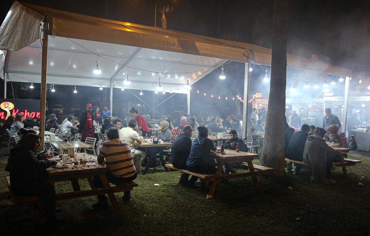 Visitors enjoy dinner under festival tents as smoke from grills fills the air during the final night of the International Taste of Adana Festival, Oct. 12, 2025. (AA Photo)