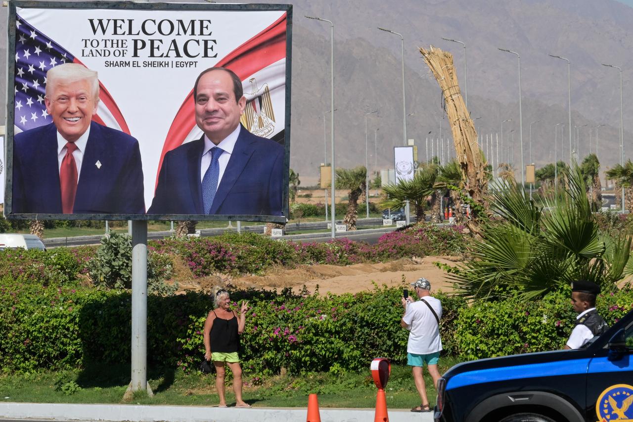 Tourists take pictures in front of a billboard bearing the portraits of US President Donald Trump and Egyptian President Abdel Fattah al-Sisi outside the congress centre ahead of the Sharm El-Sheikh Peace Summit in the Egyptian Red Sea resort town of Sharm el-Sheikh on October 13, 2025. (AFP Photo )