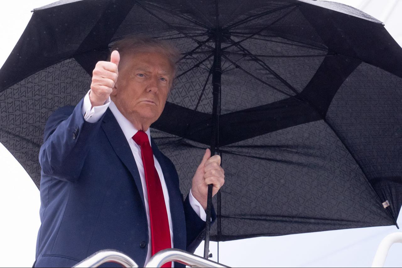 US President Donald Trump holds an umbrella as gives a thumbs up while boarding Air Force One prior to departure from Joint Base Andrews in Maryland, October 12, 2025. (AFP Photo)