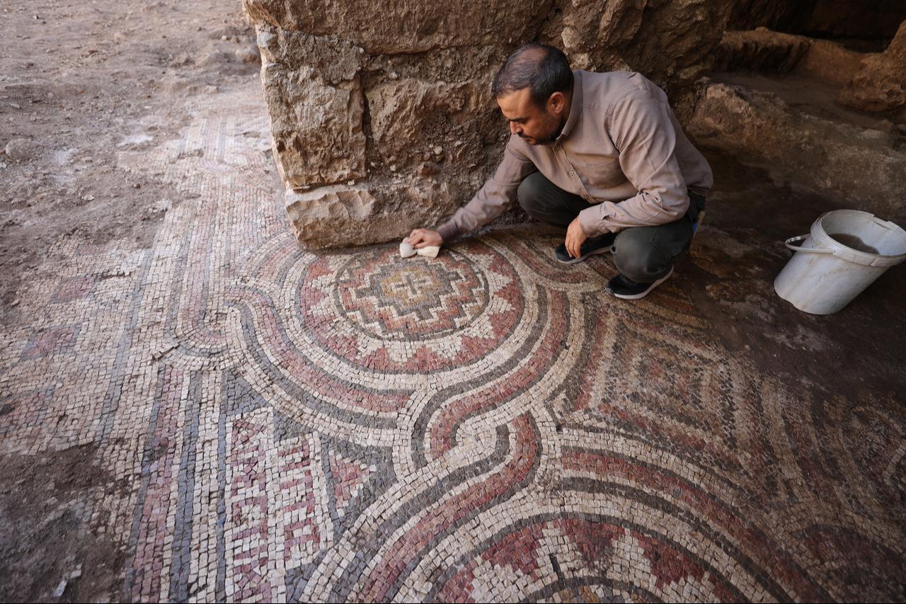 An archaeologist clean sections of a 1,500-year-old mosaic floor uncovered beneath a historic water mill in Midyat, Mardin, southeastern Türkiye, Oct. 14, 2025. (AA Photo)