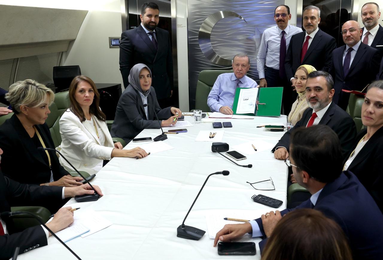 President Recep Tayyip Erdogan (C) shows journalists the text of the Sharm el-Sheikh Peace Summit Declaration on his return flight home. (Photo via Turkish Presidency/Mustafa Kamaci)
