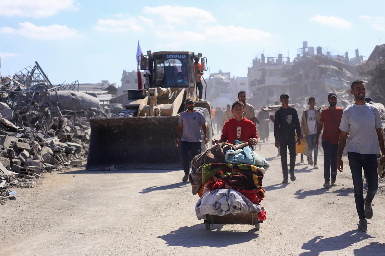 Bulldozers deployed by the Gaza Municipality drive past displaced people, on their way to clear building rubble from main axes and streets in Gaza City, amid a ceasefire between Israel and Palestinian factions, on Oct. 14, 2025. (AFP Photo)