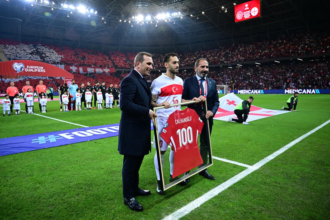 Turkish midfielder Hakan Calhanoglu (C) receives a framed jersey and plaque to mark his 100th appearance with the national team before 2026 FIFA World Cup European Qualifiers Group E football match between Türkiye and Georgia at Kocaeli Stadium in Kocaeli, Türkiye on Oct. 14, 2025. (AA Photo)