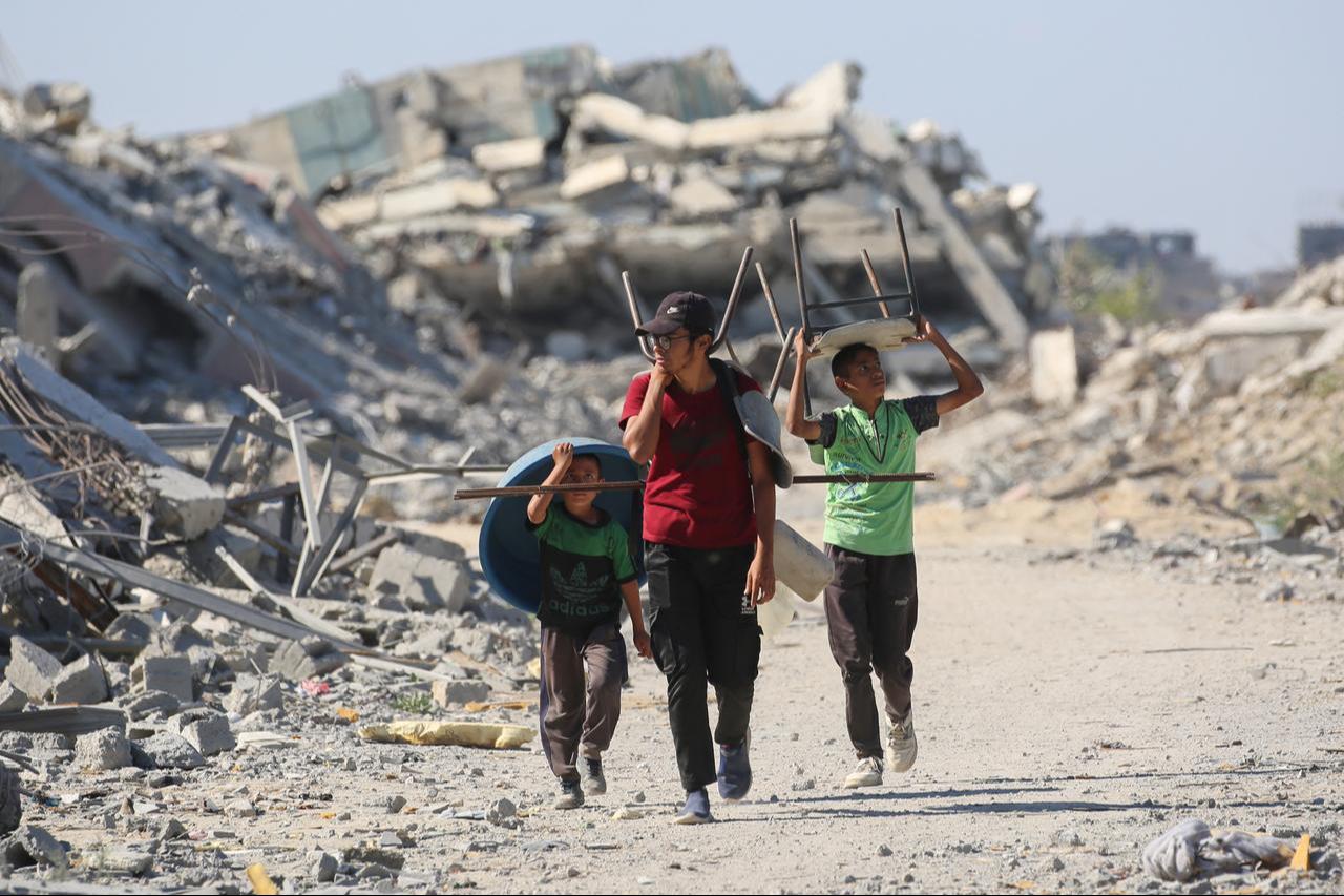Palestinians carry chairs and a plastic basin as displaced residents return to their homes in al-Zahra area, north of the Nuseirat refugee camp in central Gaza Strip, Oct. 14, 2025. (AFP Photo)