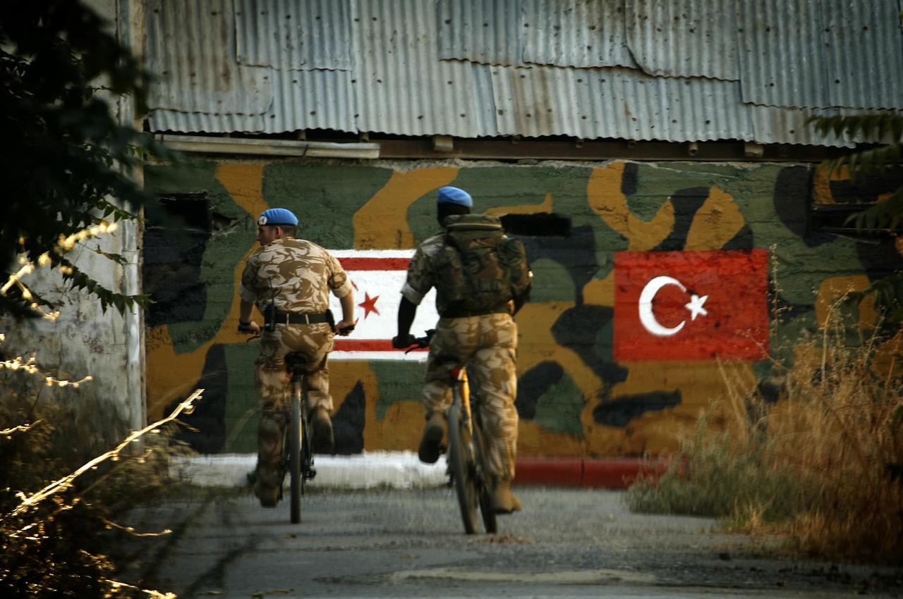 British UN soldiers ride their bicycles past a Turkish army position as they patrol the green line separating the divided Cypriot capital of Nicosia, October 16, 2009. (AFP Photo)