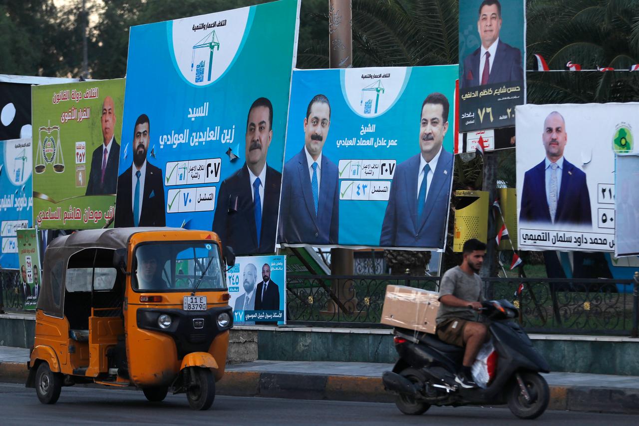 People drive their vehicles past electoral billboards  on a street in Baghdad on October 14, 2025, ahead of parliamentary elections on November 11. (AFP Photo )
