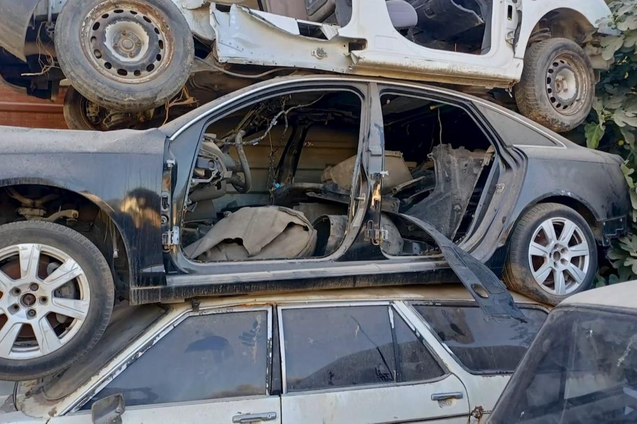 A police officer inspects dismantled and stacked car bodies at a scrapyard during nationwide “change vehicle” operations in Türkiye, where authorities targeted rings accused of altering vehicle identities to defraud buyers. (IHA Photo)