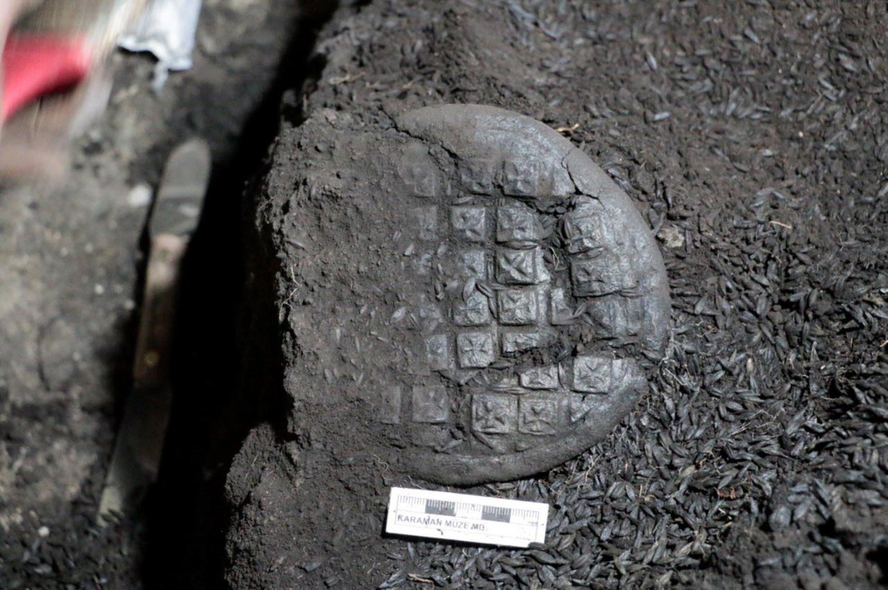A carbonized bread bearing a Maltese cross pattern found during excavations at Topraktepe in Karaman, Türkiye, Oct. 8, 2025. (Photo via Karaman Governorship)