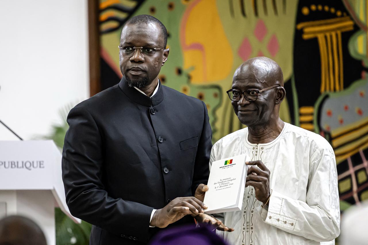 The President of the Committee for the Commemoration of the Thiaroye massacre Mamadou Diouf (R) hands over to Senegal Prime Minister Ousmane Sonko (L) the official report on the Thiaroye massacre, Dakar, Senegal, October 16, 2025. (AFP Photo)