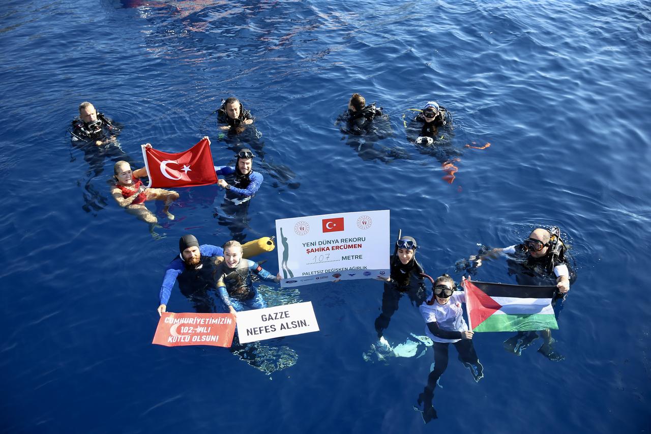 World record freediver Sahika Ercumen celebrates her 107-meter dive with her team holding Turkish and Palestinian flags, along with banners reading “Happy 102nd Anniversary of Our Republic” and “Let Gaza Breathe,” off Kas, Antalya, Türkiye, Oct. 17, 2025. (AA Photo)