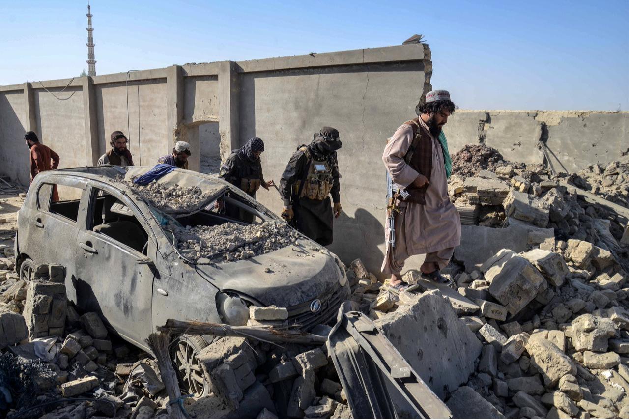 Taliban security personnel walk past a damaged car in the Spin Boldak district of Kandahar province, October 16, 2025. (AFP Photo)