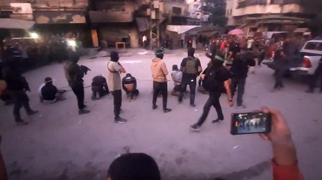 P,cture shows armed Hamas fighters standing behind blindfolded, bound and kneeling men as a crowd surrounds them in a street in Gaza City, October 13, 2025. (AFP Photo )