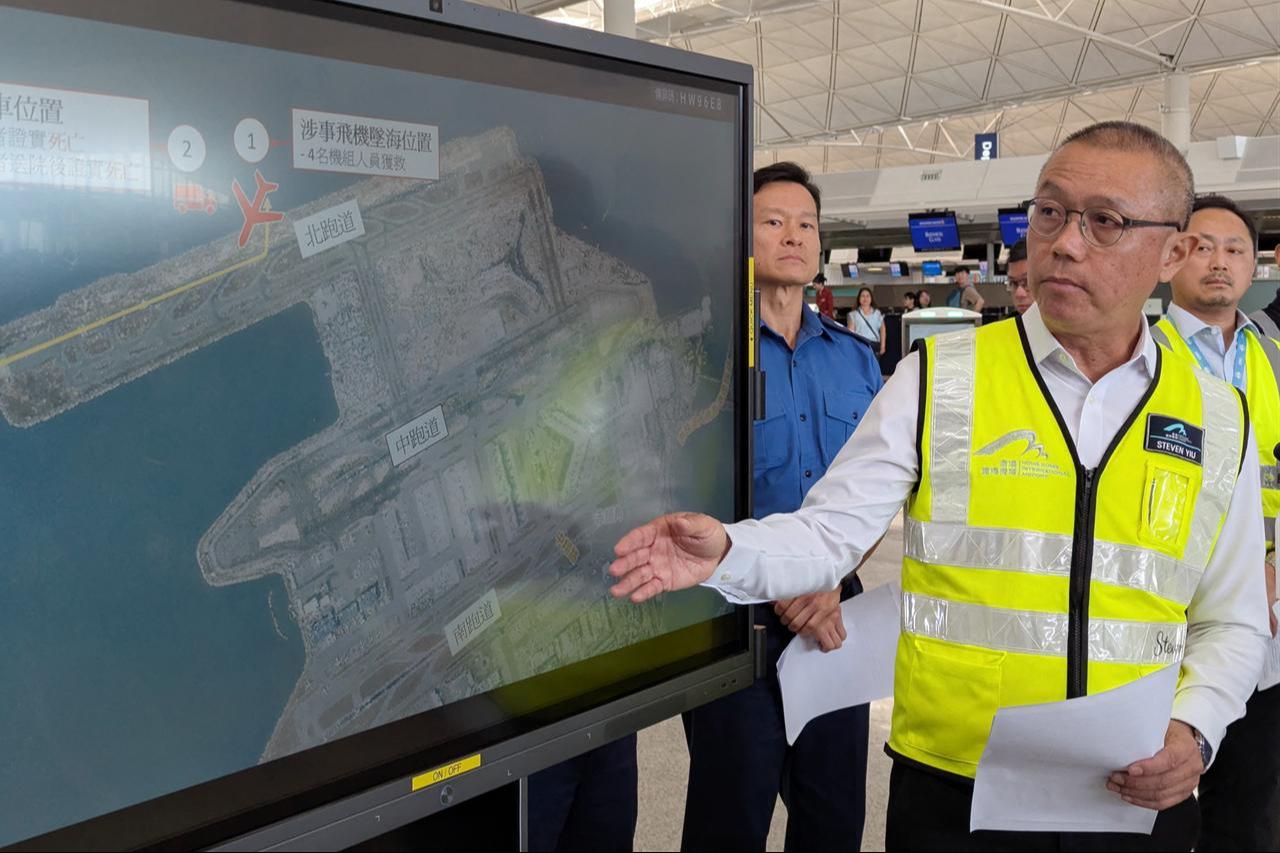 Steven Yiu, Airport Authority Hong Kong's executive director of airport operations, speaks while standing beside a screen showing the location where a Boeing 747-400 cargo aircraft skidded into the sea on Hong Kong's international airport on Oct. 20, 2025. (AFP Photo)