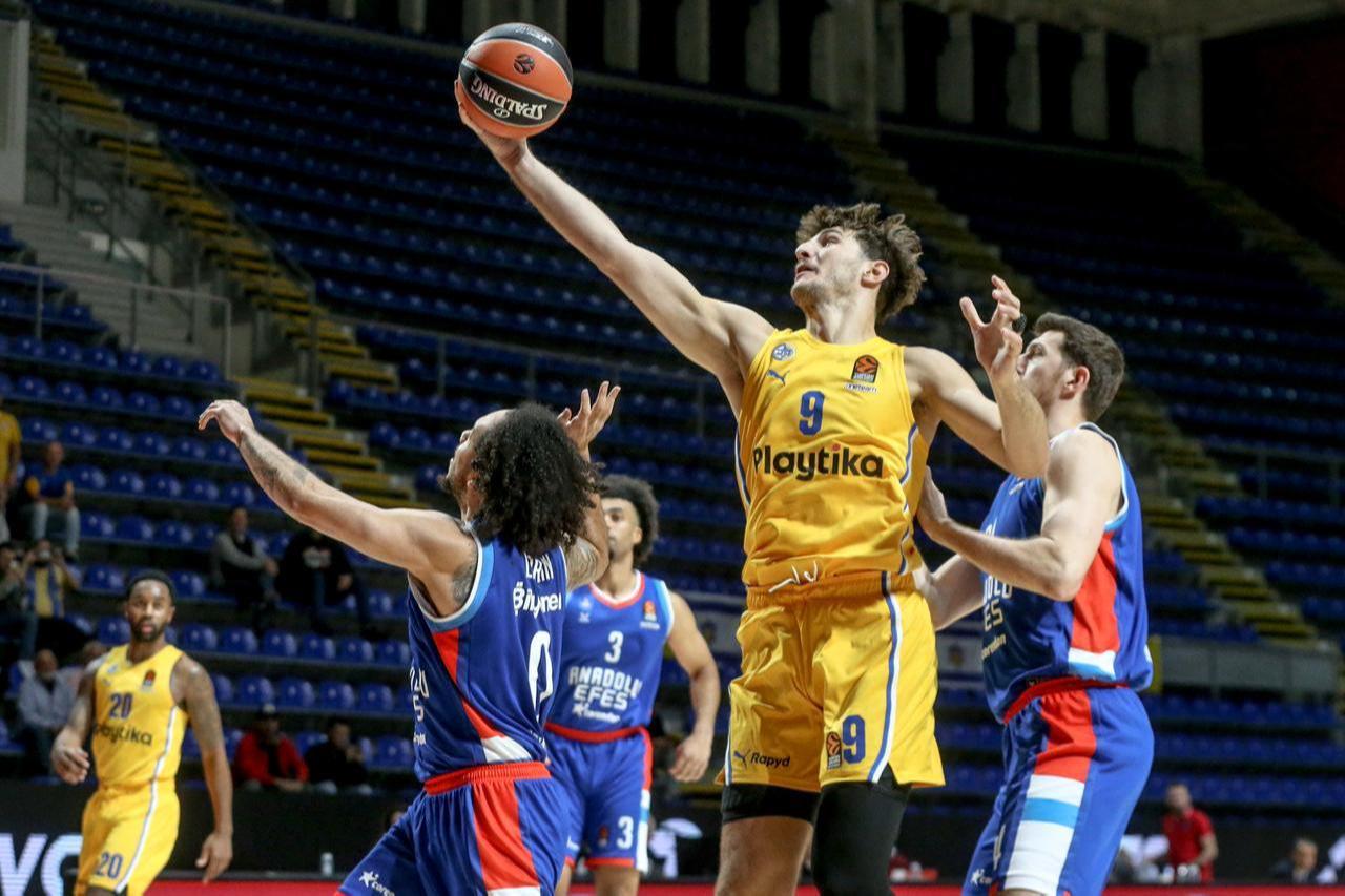Maccabi Playtika player Roman Sorkin (#9) in yellow uniform reaches for the ball against Anadolu Efes defenders during Week 3 of the Turkish Airlines EuroLeague match at Aleksandar Nikolic Hall in Belgrade, Serbia. The game was played on neutral ground, with Sorkin elevating above blue-uniformed Anadolu Efes players attempting to block his shot in Belgrade, Serbia on Oct. 16, 2024. (AA Photo)