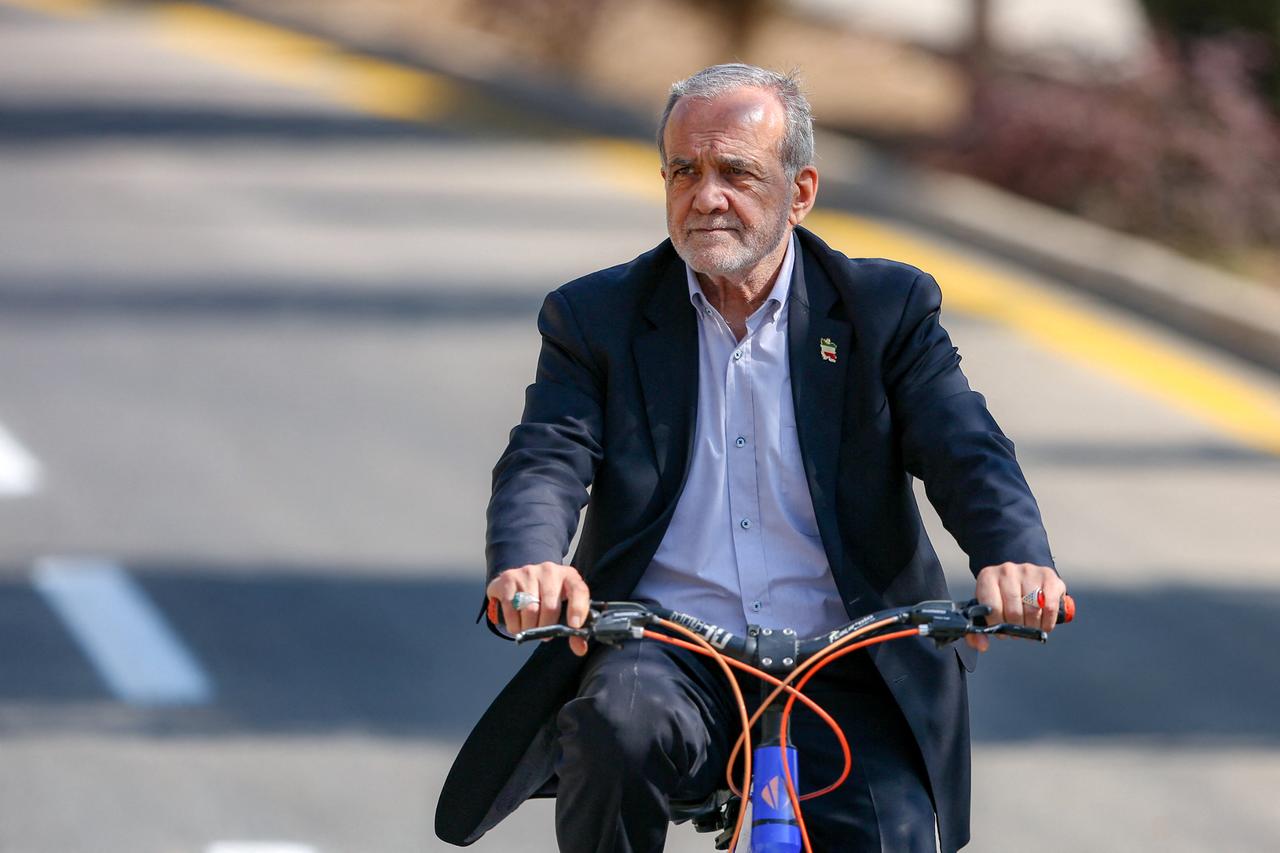Iranian President Masoud Pezeshkian riding a bicycle during a visit to Isfahan, October 16, 2025. (Photo by Iranian Presidency/AFP)