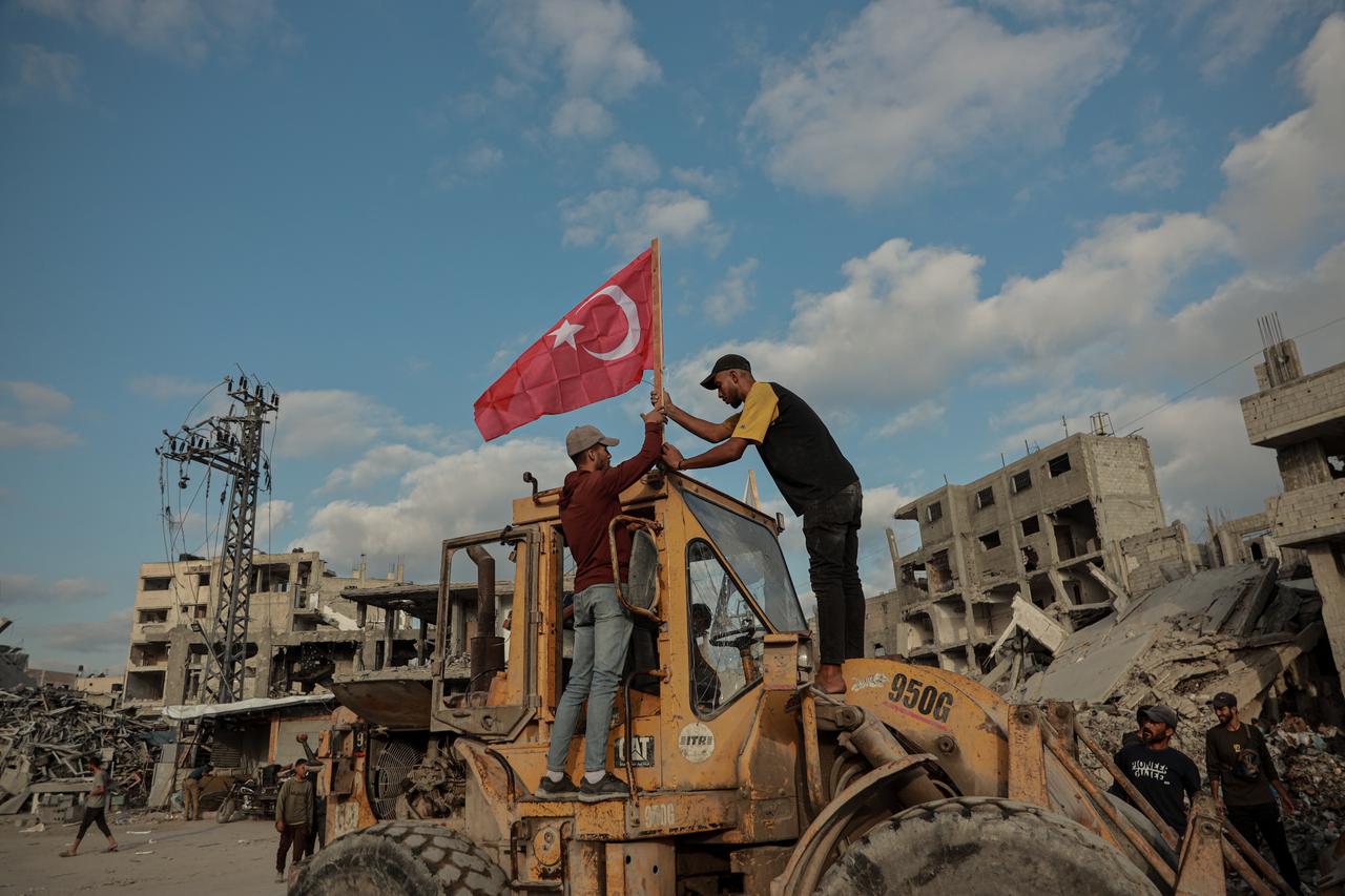 The photo shows a person attaching a Turkish flag to an excavator, which began clearing the rubble of buildings destroyed by Israeli attacks in Gaza City, October 18, 2025. (AA Photo)