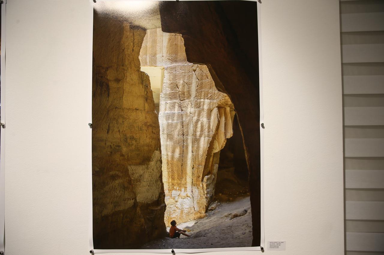 A child sits beneath massive stone formations in one of Sanliurfa’s ancient quarries, a reminder of the city’s millennia-old craftsmanship and sacred landscapes, featured in the “Sanliurfa Tracing a Rich Heritage” exhibition in Vienna, Austria, Oct. 22, 2025. (AA Photo)
