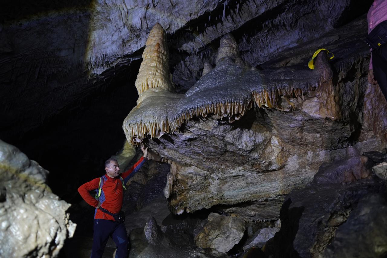 A visitor examines stalactites and stalagmites formed by mineral deposits inside Kuneba Cave in Sulaymaniyah, Iraq, Oct. 24, 2025. (AA Photo)