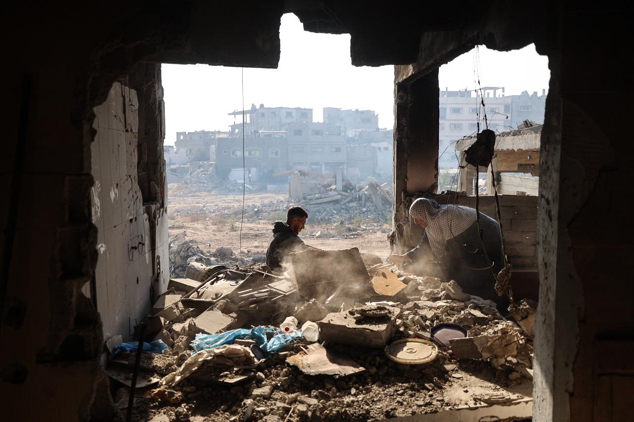 A displaced Palestinian woman, swifts through debris with her grandson upon returning to her home, which was heavily damaged by Israeli bombardments in Bureij refugee camp, in central Gaza Strip, Oct. 23, 2025. (AFP Photo)