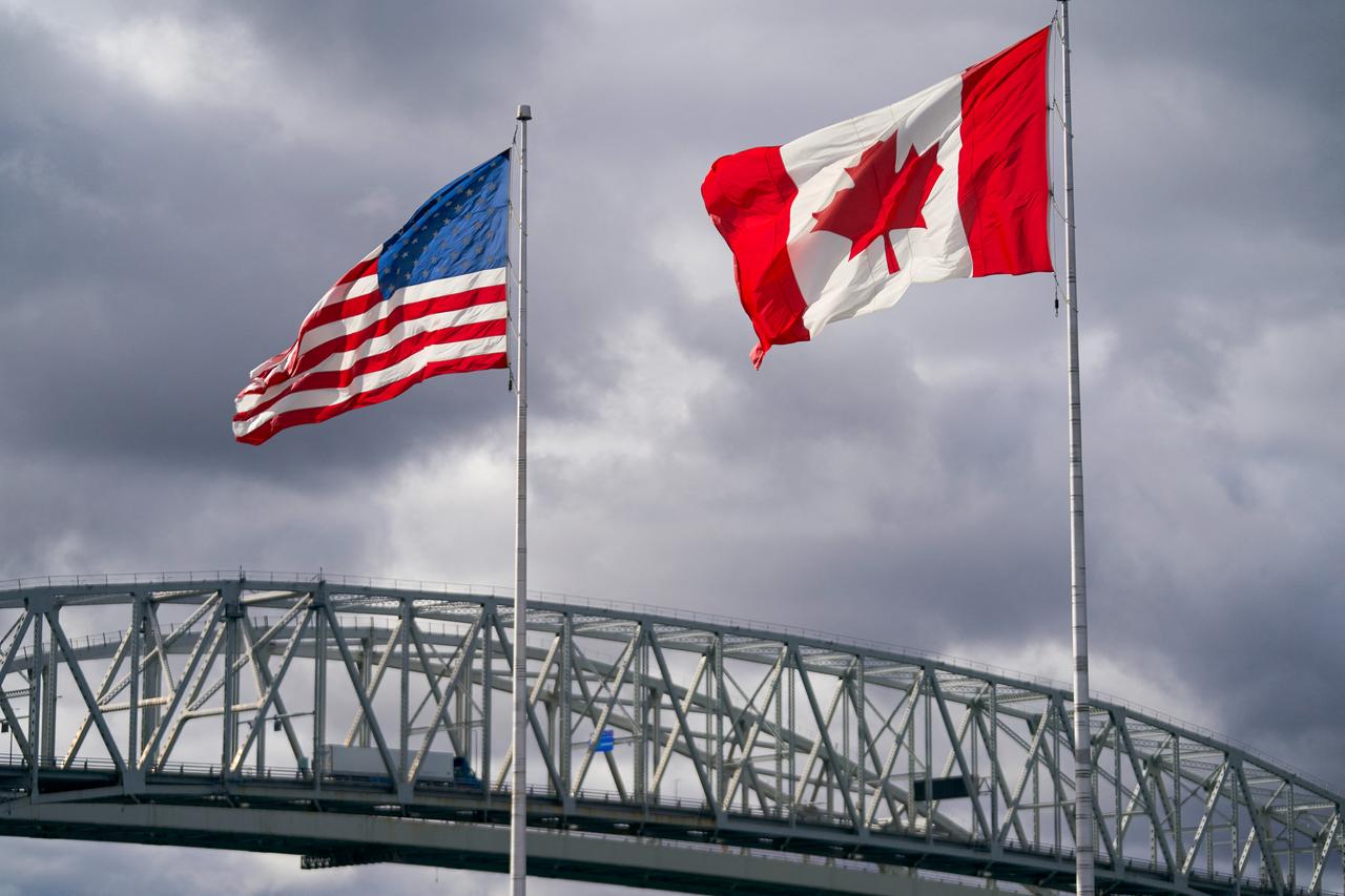 The US and Canada flags flutter next to the Blue Water Bridge border crossing in Point Edward, Ontario, on Oct. 24, 2025. (AFP Photo)